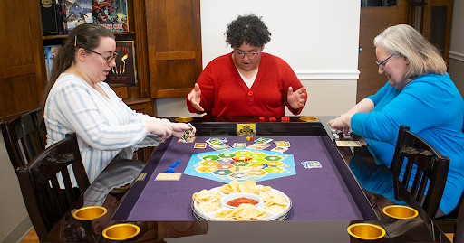 People Sitting at Breakfast Table Playing Settlers of Catan - Carolina Game Tables